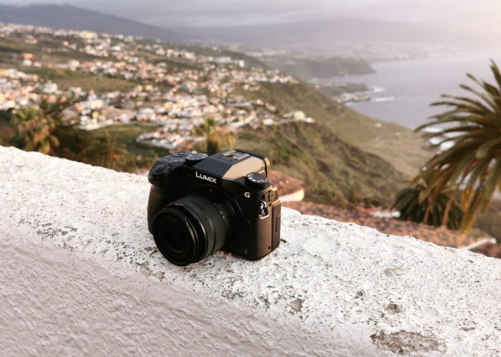 Panasonic Lumix DMC-G685 sitting on a ledge overlooking beautiful scenery, including a large body of water. 