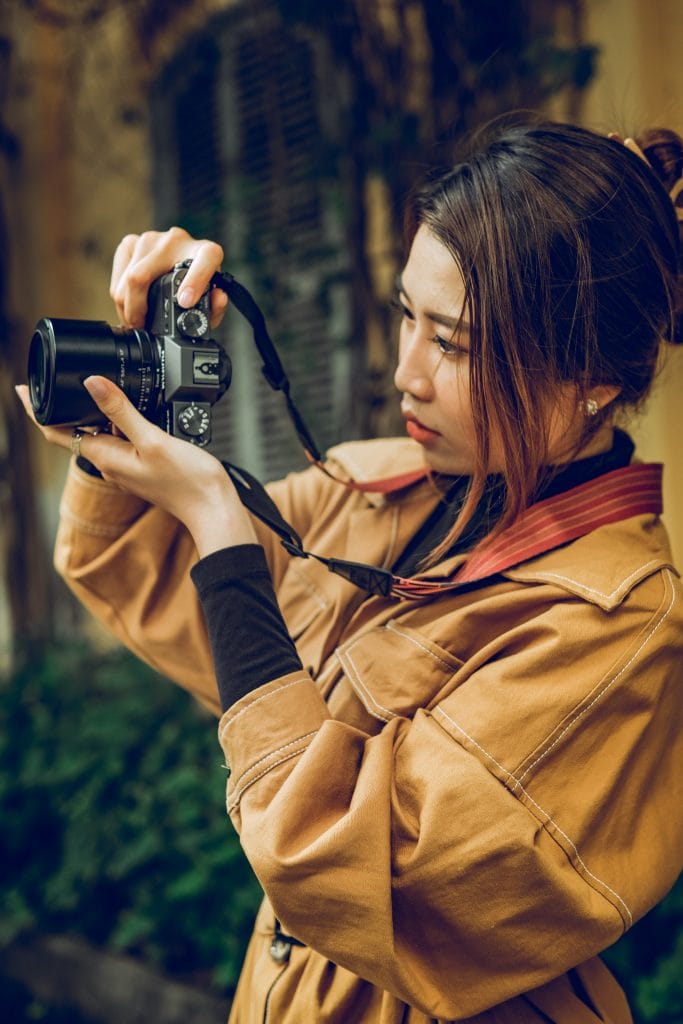 Young woman in a trenchcoat shooting a mirrorless camera. 