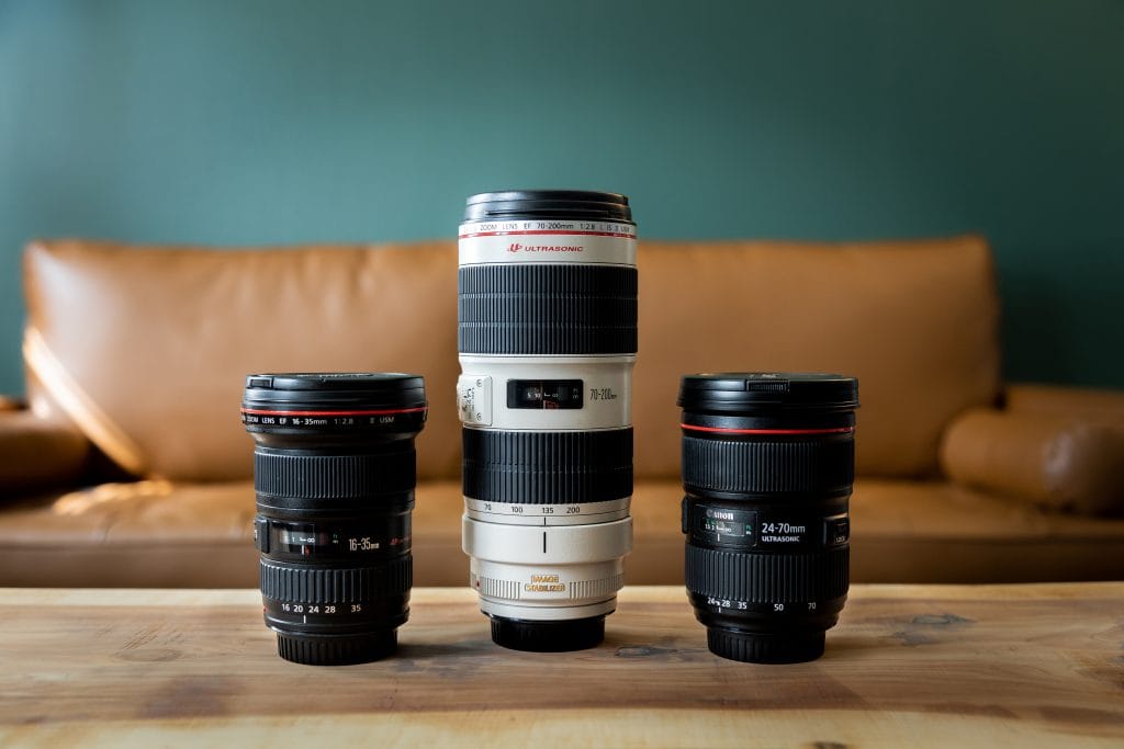Three lenses for wildlife photography on a wood table with a couch in the background